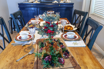 Roasted goose with a maple glaze and cloves on a Christmas table with cranberry sauce, sweet potatoes