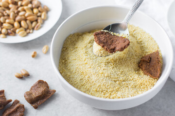 kuli-kuli and yellow garri in a white bowl, top view of nigerian groundnut cakes and garri in a bowl, fresh homemade nigerian kulikuli and cassava in a ceramic bowl