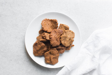 Overhead view of kuli-kuli on a white plate, top view of nigerian groundnut cakes on a plate, fresh homemade nigerian kulikuli on a ceramic plate