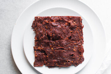 Overhead view of Nigerian kilishi on a white plate, top view of nigerian spicy beef jerky, flatlay of dried beef suya