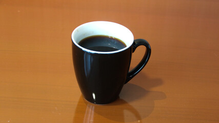 Hot black coffee with latte art milk foam in mug cup on wooden table over view. As breakfast In a coffee shop in a cafe, during business work concept, vintage style