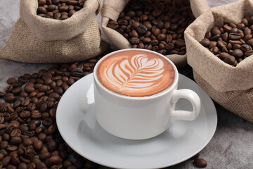 Cup of coffee and beans on dark cement background.