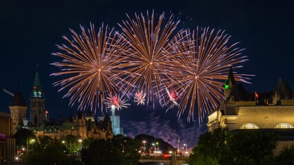 A golden burst of fireworks illuminates a historic skyline at night, creating a stunning display of light and color. 