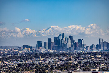 View over Los Angeles Skyline in California with snow covered mountains in the background. Visible are San Gabriel and San Bernardino mountains. 