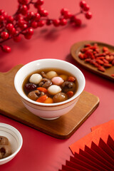 Red and white tangyuan with syrup soup, dried longan pulp, red dates for Chinese lunar new year.