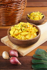Cassava chips in a wooden bowl on a wooden base photographed with studio light with a traditional theme