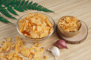 Cassava chips in a clear glass bowl on a plywood base photographed with studio light