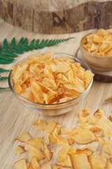 Cassava chips in a clear glass bowl on a plywood base photographed with studio light