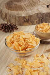 Cassava chips in a clear glass bowl on a plywood base photographed with studio light