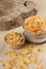 Cassava chips in a clear glass bowl on a plywood base photographed with studio light