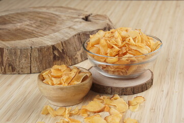 Cassava chips in a clear glass bowl on a plywood base photographed with studio light