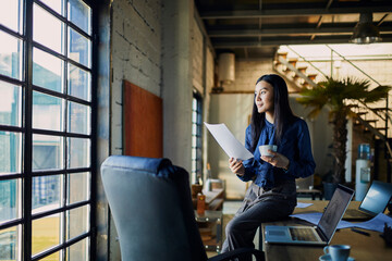 Professional woman reviewing documents in modern industrial office setting