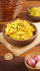 Cassava chips in a wooden bowl on a wooden base photographed with studio light with a traditional theme