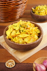 Cassava chips in a wooden bowl on a wooden base photographed with studio light with a traditional theme
