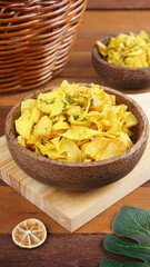 Cassava chips in a wooden bowl on a wooden base photographed with studio light with a traditional theme