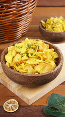 Cassava chips in a wooden bowl on a wooden base photographed with studio light with a traditional theme