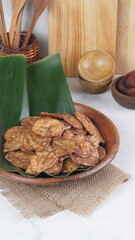 Indonesian chocolate flavored banana chips on a clay plate with a traditional property theme photographed with studio light