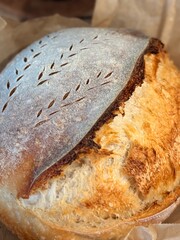 Artisan sourdough bread featuring a delightful golden crust and intricate scoring, showcasing its texture and freshness. Perfect for examples of homemade baking and rustic cozy foods.