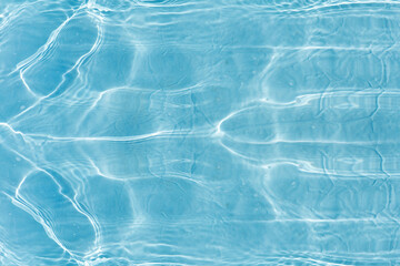 Blue water with ripples on the surface. Defocus blurred transparent blue colored clear calm water surface texture with splashes and bubbles. Water waves with shining pattern texture background.