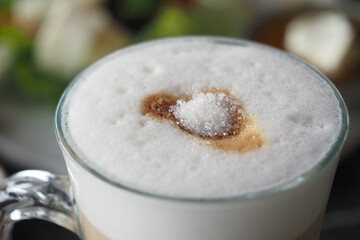 white sugar pouring from a in a paper packet on a coffee cup 