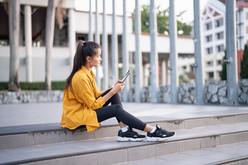 Smiling young Asian woman using digital tablet in urban city