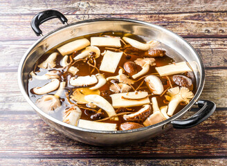 Wild mushroom soup pot served in steel pot isolated on wooden table side view of hong kong food