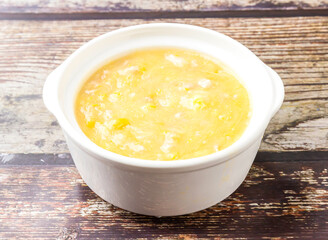 Chicken and corn soup served in broth isolated on wooden table side view of hong kong food