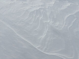 Snow Dune. Abstract natural background of snow dunes and snow drifts. Strong wind makes bizarre snow patterns and textures on the surface of the field