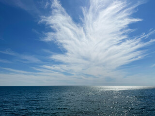 Beautiful sky clouds over ocean sea shiny blue water.
