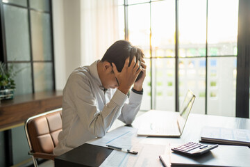 Asian Business man tiredness and stress while having headache. Painful men are stressed at work in office