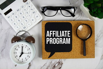 Affiliate Program text on speech bubble with alarm clock, calculator and magnifying glass  on marble background