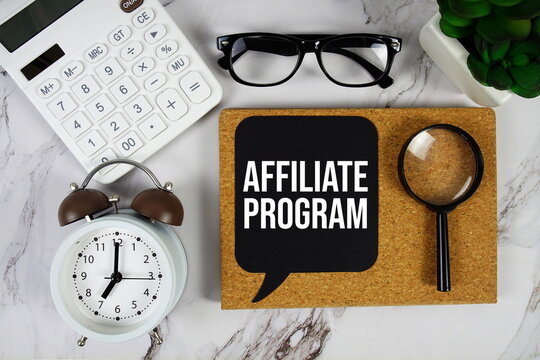 Affiliate Program text on speech bubble with alarm clock, calculator and magnifying glass  on marble background