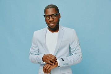 Stylish young man in a light blue suit with glasses against a soft blue background, exuding...