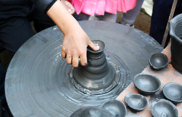 A young hand shaping clay on a spinning pottery wheel, highlighting traditional art, creativity, and hands-on learning in pottery making.