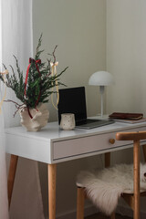 Christmas interior. Christmas bouquet, laptop, lamp, cup of coffee on the desktop in the living room