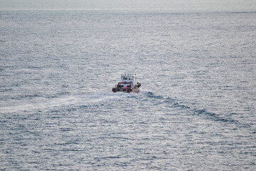 a boat sails on the ocean, leaving traces of waves