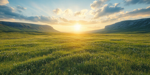 Obraz premium Golden sunrise over a tranquil valley with lush green grass and distant mountains