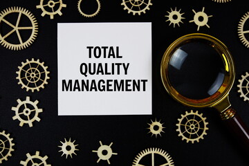 Total Quality Management (TQM) text with magnifying glass on black background
