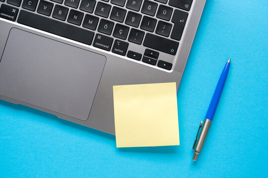 Top view of blank post-it stuck on laptop on blue table