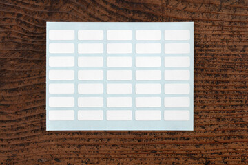 white labeling stickers with blue backing sheet, isolated on Old rustic work table.