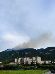 Residential buildings near lush mountains with rising smoke. Torre Del Greco, Italy.