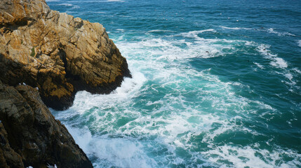 Tall Lighthouse Standing on Cliff Overlooking the Ocean Waves and Rocky Shore