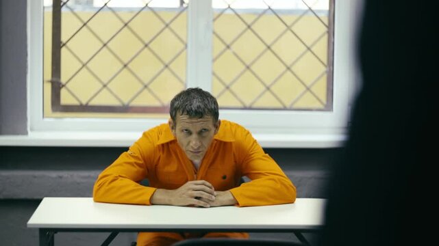 A prisoner in prison looks at the visitor.