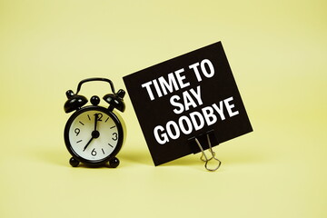 Time to say Goodbye text message on paper card with alarm clcok on yellow background