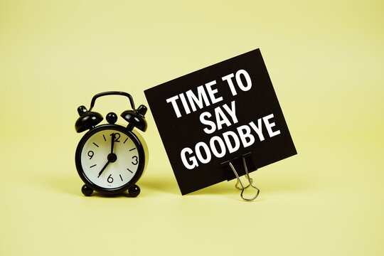 Time to say Goodbye text message on paper card with alarm clcok on yellow background