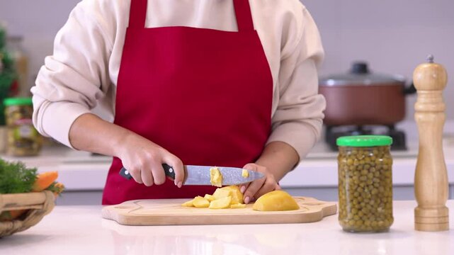 Close up view of male hands chopping potato on wooden cutting board with knife	
