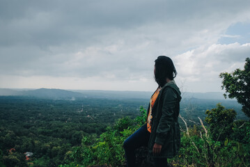 Naklejka premium A woman alone on the edge of a cliff and watching the deep valley. Woman sitting alone on mountain cliff to see the view
