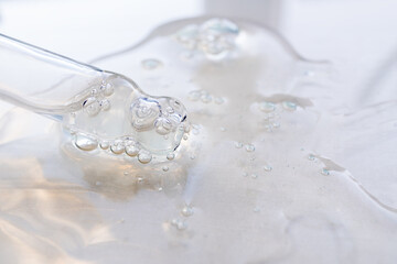 A drop of cosmetic aromatic oil drips from the pipette. Front view.