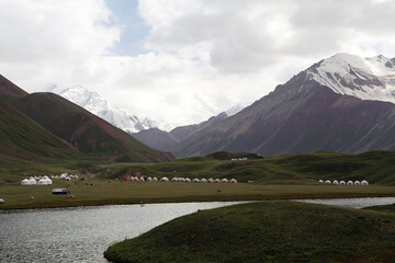 Fototapeta premium Yurt camp at Tulpar Kul Lake at the foot of Lenin Peak in the Pamir Mountains in Kyrgyzstan