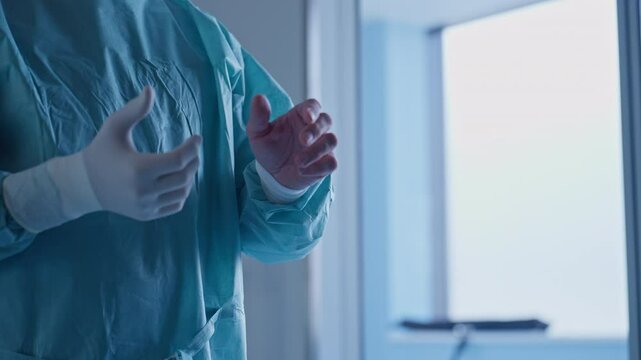 Close-up of medical professionals in surgical gowns and gloves preparing for a procedure, focusing on teamwork in a sterile environment. Concept of healthcare preparation and medical teamwork - Powered by Adobe